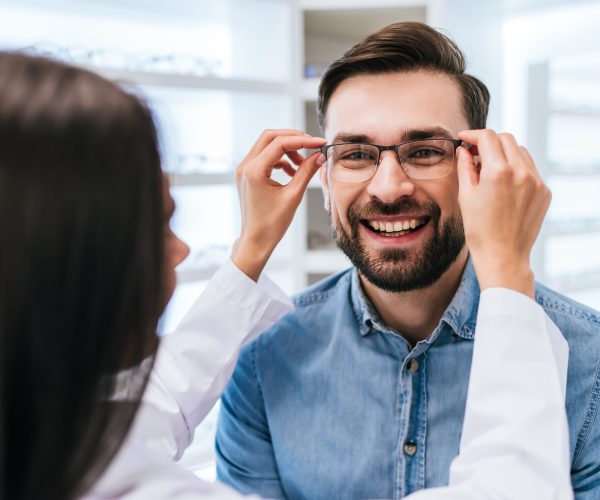 Young,Female,Doctor,Ophthalmologist,Is,Helping,Handsome,Man,To,Choose